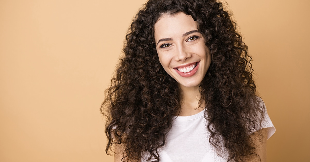 mulher negra sorrindo. Ela veste branco.